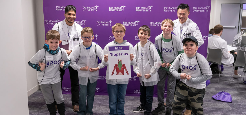 Two medical students pose with elementary school boys