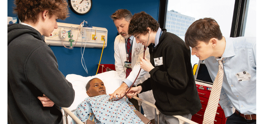 Dr. Bidey instructs high school students on how to use a stethoscope