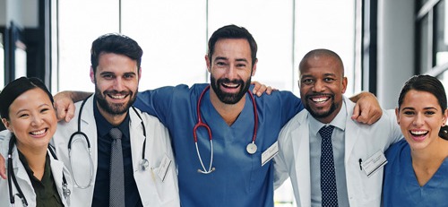 5 smiling doctors in white coats with stethoscopes