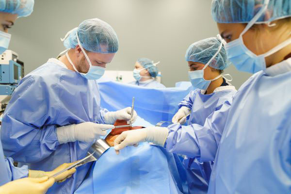 Students in blue scrubs practicing surgery on a simulated patient.