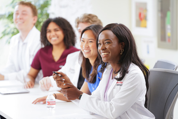 Smiling UIWSOM medical students in a classroom.
