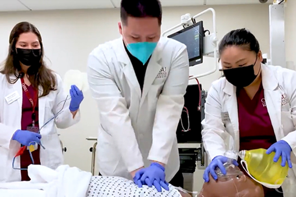 Three students practicing heart compressions on a simulated mannekin