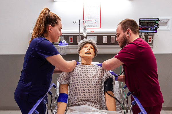 DMUCOM students practicing a medical procedure on a simulated patient.
