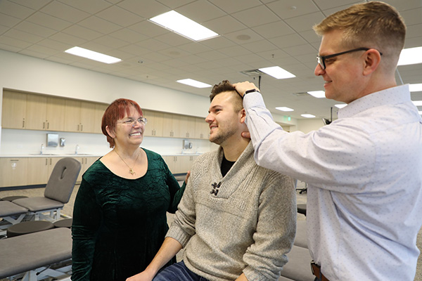 MCOM student practicing OMM on a fellow student while observed by faculty.