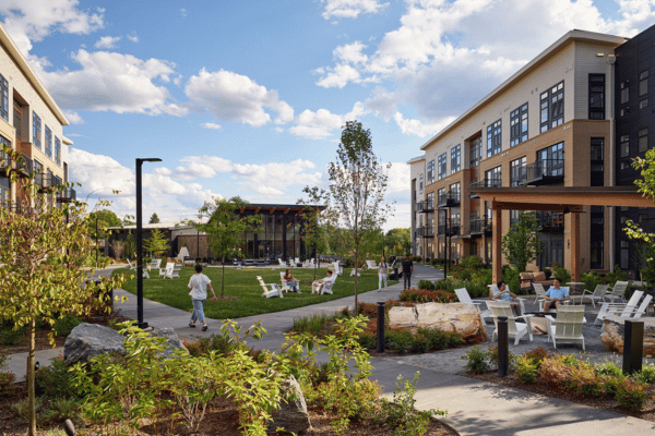 MSOM campus building and green space with students walking and sitting outside.