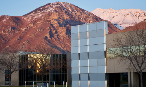 Dramatic photo of Noorda COM campus building with red and snow-capped mountains in the background