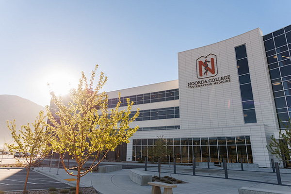 Noorda COM campus building with trees in front and a mountain background