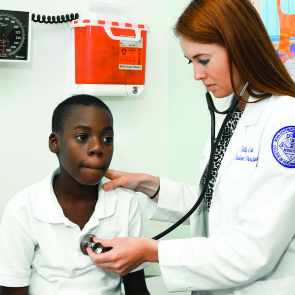 Female med student using a stethoscope to check a boy's heartbeat