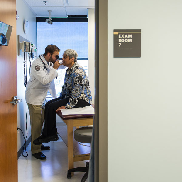 PCOM student examining a patient for head and eye issues.