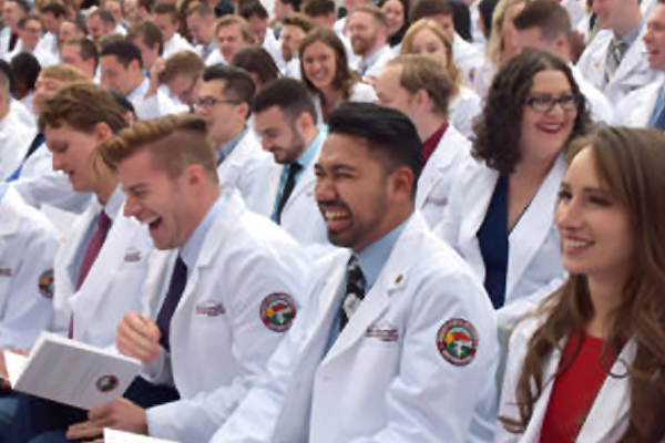 RVU students in whitecoats laughing at an assembly