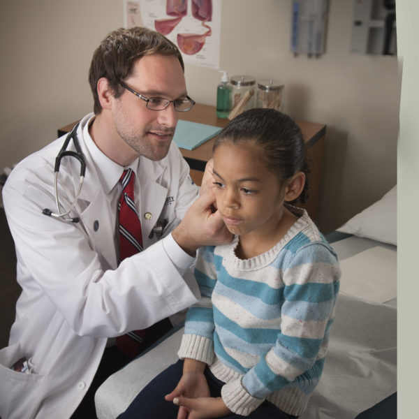 Doctor examining a young girl's ear.