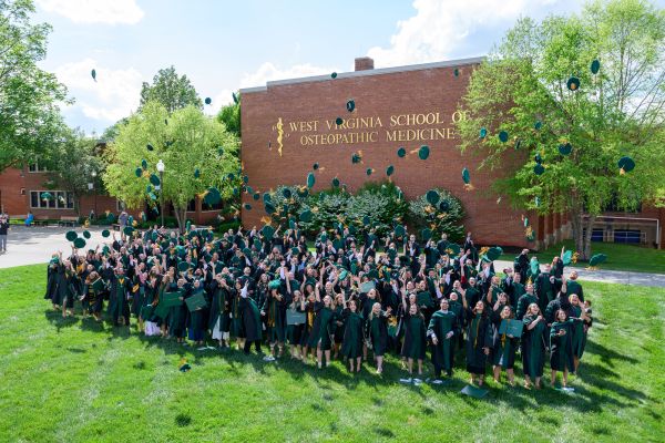 New WVSOM DO graduates toss their mortar board hats in celebration.