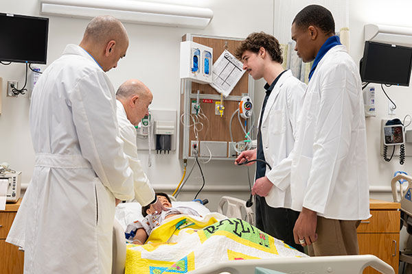 COM professors train 2 medical students on a simulated patient.