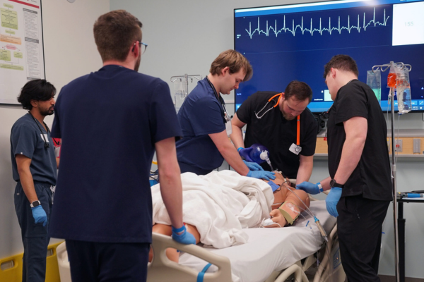 Medical team in scrubs urgently tends to a patient in a hospital bed.