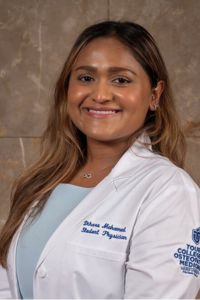 Dihara smiling in her whitecoat for a professional headshot