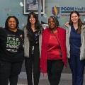 AdiversegroupofhealthcareworkersandstudentsstandsmilingtogetherinsideaPCOMHealthCenter