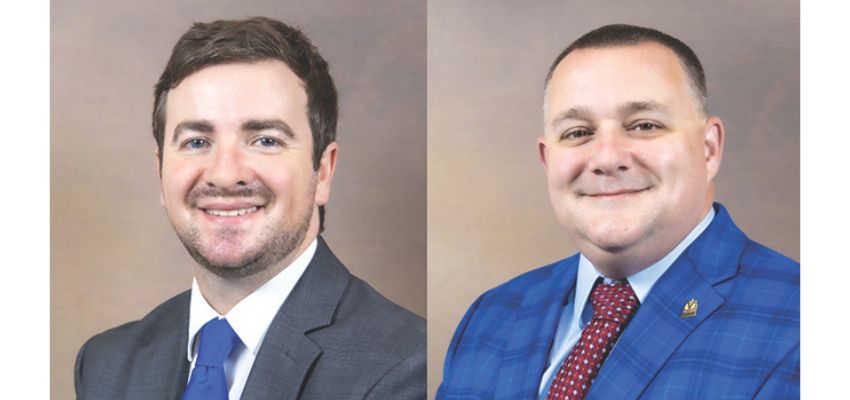 A side-by-side portrait of two men in suits smiling against a neutral background.