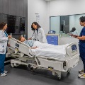 ThreeUNTHSC-TCOMstudentsandafacultymemberstandaroundahospitalbedengaginginasimulatedpatientcareexerciseinamodernclinicalskillslab
