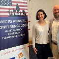 TwoVCOM-LouisianaattendeesstandbesideabannerpromotingtheAMOPSAnnualConference2025inConroeTexas