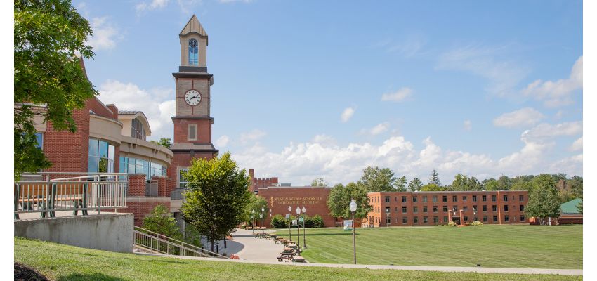View of the West Virginia School of Osteopathic Medicine (WVSOM) campus with its signature clock tower and open green space.