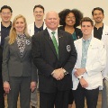 Agroupofmedicalstudentsandfacultysomeinwhitecoatsposeforaphototogetherinaclassroomsetting