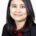 Awomaninbusinessattiresmilesforaheadshotwithawhitebackground
