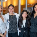 Fourfemalestudentsdressedinbusinessormedicalattiresmileforaphotoinabrightlobbyarea