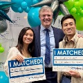 TwostudentsholdIMATCHEDsignsalongsideafacultymemberduringMatchDaycelebrations