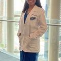 Amedicalstudentinawhitecoatsmileswhileposinginabrightlylitindoorspace