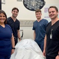 Fourmedicalstudentsinscrubsposeinaclinicalsimulationroom