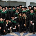 Alargegroupofgraduatingmedicalstudentsinacademicregaliaposetogetherindoorssmilingatthecamera