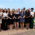 AgroupofVCOM-Louisianastudentsandfacultyposewithawardsonarooftopterraceoverlookingascenicbackdrop