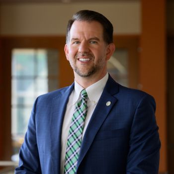 A professionally dressed man smiles while posing indoors at the West Virginia School of Osteopathic Medicine (WVSOM).
