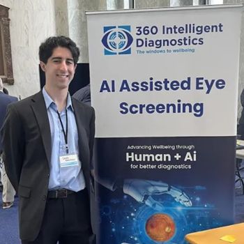 A student stands next to a display booth promoting AI-assisted eye screening at a healthcare or technology event.