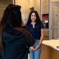 Astudentisbeingfilmedandinterviewedinamedicalschoollobbyspeakinginfrontofacameraonatripod