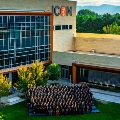 AlargegroupofstudentsposeforaphotooutsidetheIdahoCollegeofOsteopathicMedicinewithtreesandmountainsinthebackground