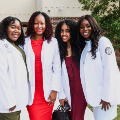 Fourwomenstandsmilingoutsidedonningtheirnewwhitecoats