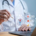 Closeofuphandsfromapersoninawhitelabcoatandstethoscopepointingapenatavirtualmedicalchart