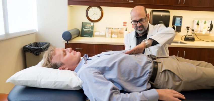A doctor uses his hands to diagnose a patient who is on a table