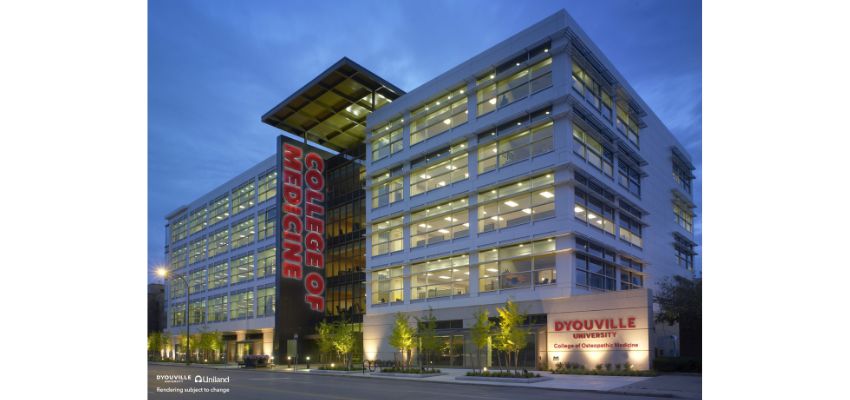 Exterior view of D’Youville University College of Osteopathic Medicine building lit up in the evening with a large “College of Medicine” sign.