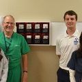 Sixmedicalprofessionalsandstudentssmileforagroupphotoinaclinicalsettingwearingscrubsandwhitecoats