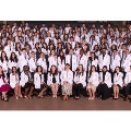 Largegroupofmedicalstudentsinwhitecoatsposeforaclassphotoseatedandstandinginseveralrowsinsideanauditorium