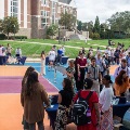 Studentsgatheroutdoorsaroundtablesoncolorfulcourtsduringacampusevent