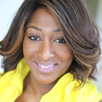 Brook smiles at the camera, wearing a vibrant yellow shirt.
