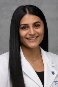 Student doctor Sneha smiles for a headshot wearing her white coat.