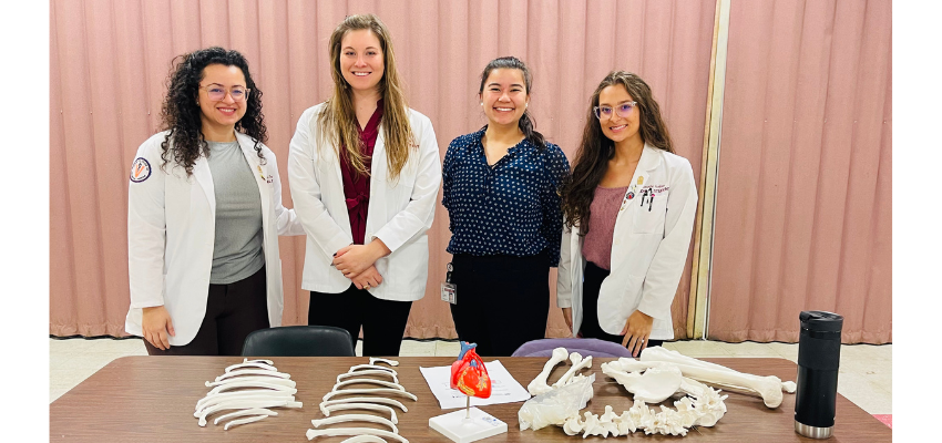 Four medical students stand in front of bones