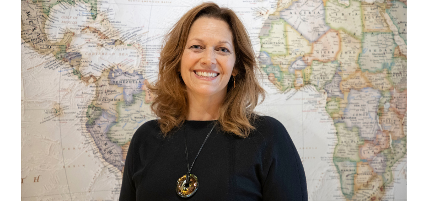 New assistant dean stands in front of world map