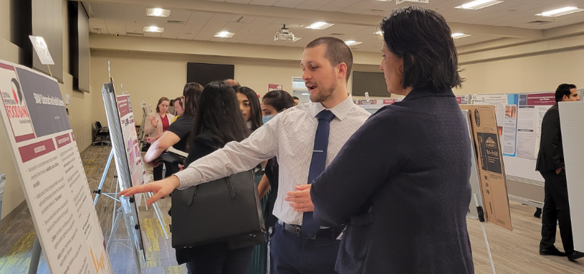 Student explains research while pointing to poster