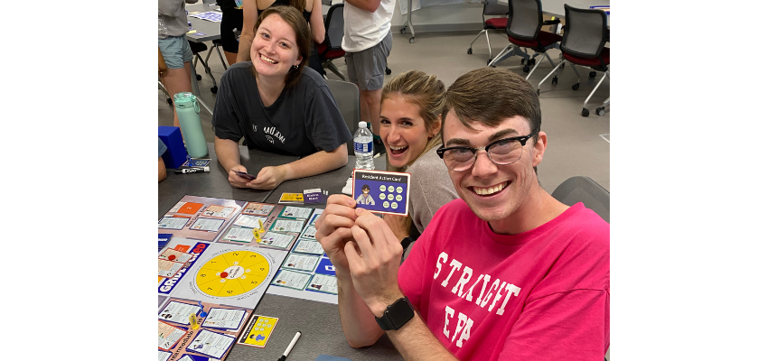 Students hold up board game pieces