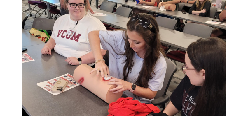 Medical student practices placing gauze over wound.